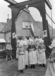836426 Afbeelding van een groep meisjes in klederdracht bij een bruggetje te Volendam.